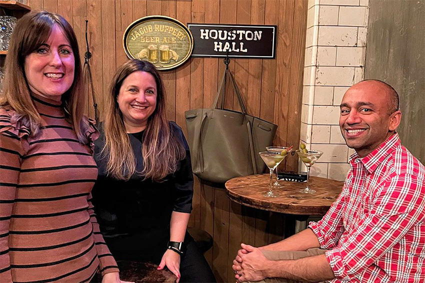 Two women and a man smiling at the camera in the VIP Tap Room at our SoHo holiday party restaurant.